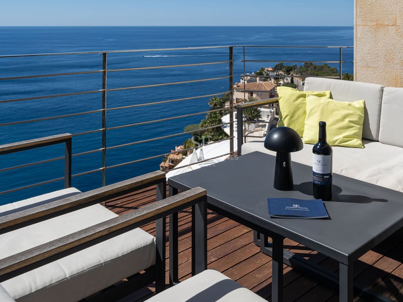 Terrasse moderne avec mobilier de salon et revêtement en bois surplombant la mer Méditerranée.