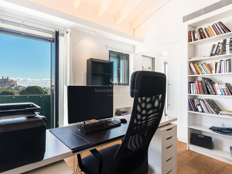 Bureau moderne avec bureau, chaise ergonomique et grande bibliothèque face à une fenêtre donnant sur la cathédrale.