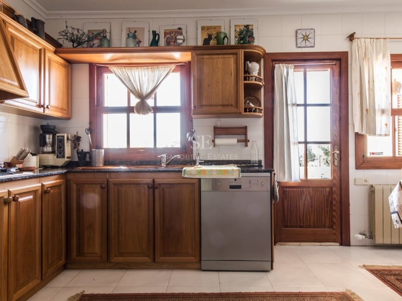 Cuisine lumineuse avec des meubles en bois chaleureux, des carreaux blancs et des plans de travail en granit.