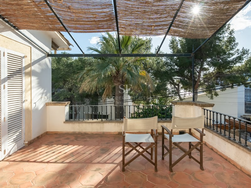 Terrasse ensoleillée avec carrelage en terre cuite, chaises de metteur en scène et pergola en canisse.