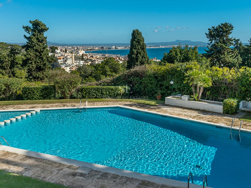 Vaste terrasse avec vue sur la mer. Mobilier moderne, piscine à débordement, rambarde en verre et élégants transats.