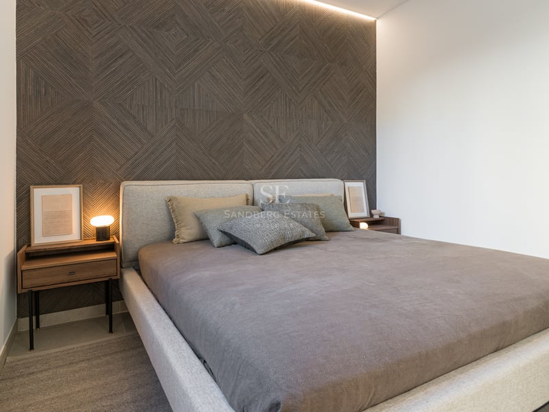 Chambre moderne avec mur d'accent géométrique en bois, lit rembourré gris et tables de nuit en noyer.
