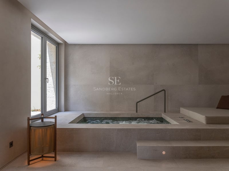 Spa intérieur en pierre avec piscine d'hydromassage encastrée, lit de repos et lumière naturelle.
