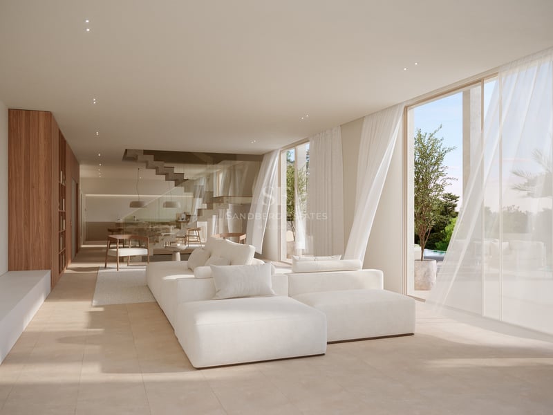 Salon lumineux avec grand canapé modulable blanc, baies vitrées et sol en pierre naturelle.