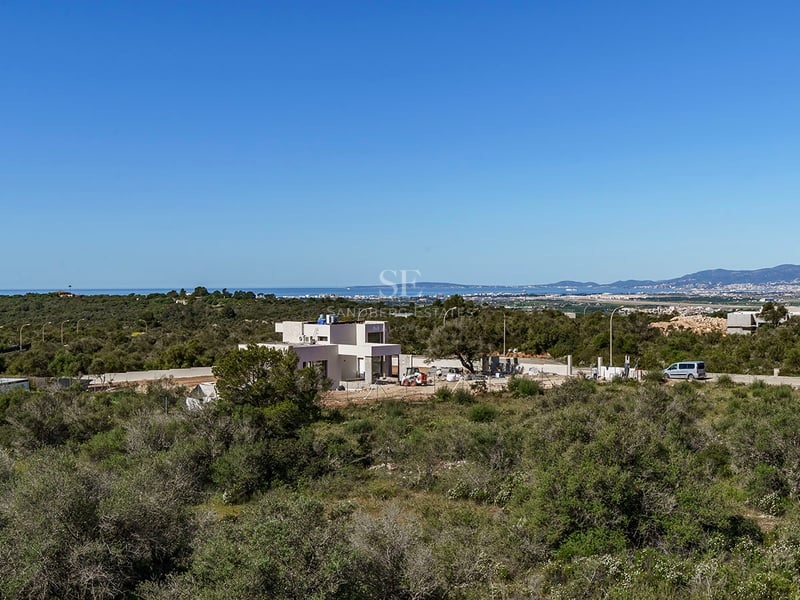 Vue extérieure d'une villa contemporaine blanche en construction surplombant la côte méditerranéenne.