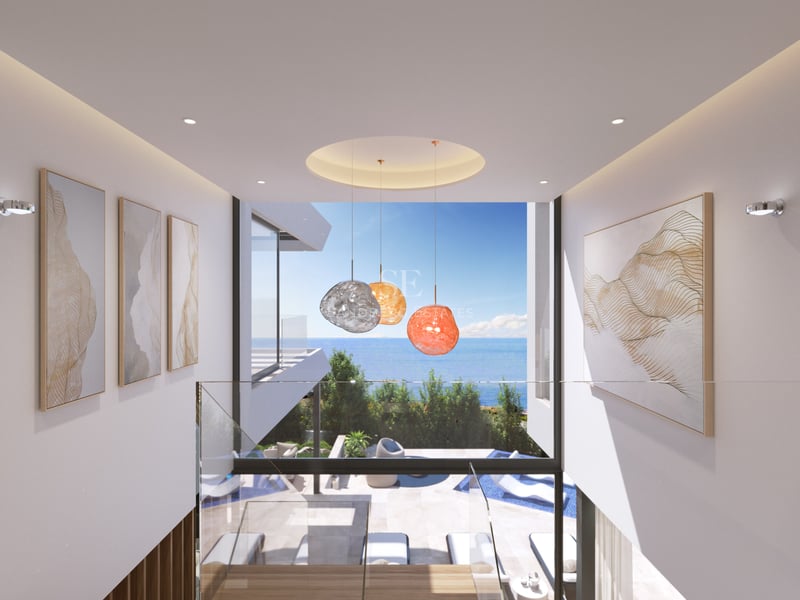 Vue d'un couloir moderne avec garde-corps en verre donnant sur une grande fenêtre avec vue sur la mer et la piscine.