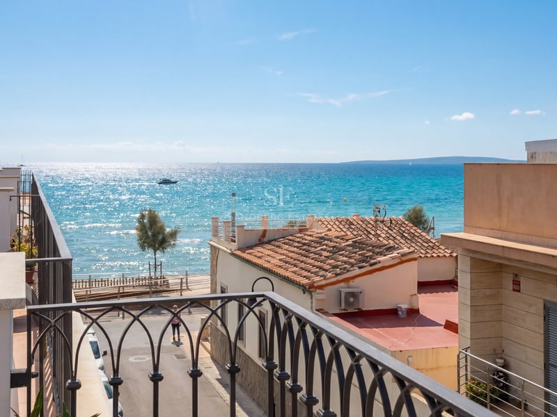 Vue depuis un balcon en fer forgé surplombant des toits en terre cuite vers la mer turquoise et l'horizon.