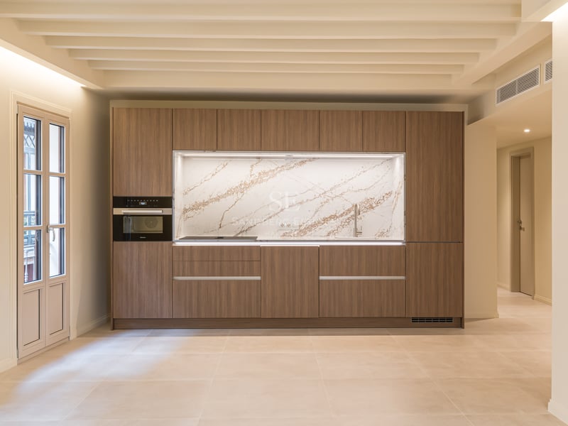 A contemporary kitchen featuring walnut cabinetry, a veined marble backsplash, and integrated Miele appliances.