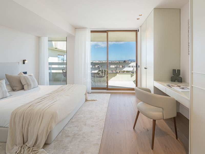 Chambre lumineuse avec parquet en chêne, bureau intégré et baies vitrées ouvrant sur une terrasse ensoleillée.
