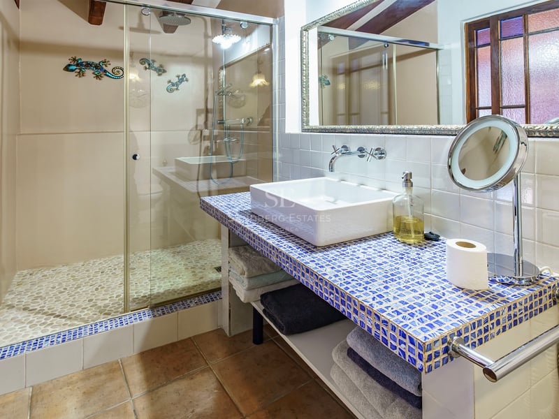 Salle de bain moderne avec douche à l'italienne au sol en galets et plan vasque en mosaïque bleue.