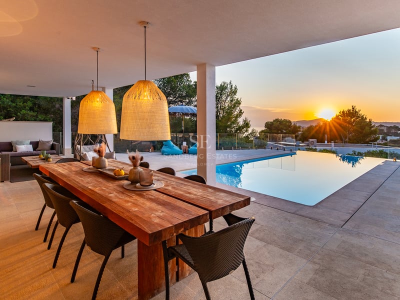 Vue extérieure d'une villa moderne avec piscine à débordement, terrasse, jardin luxuriant et grandes baies vitrées offrant une lumière naturelle.