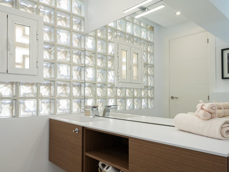 Salon spacieux avec baies vitrées offrant une vue panoramique sur la mer, parquet clair et mobilier moderne dans des tons neutres.