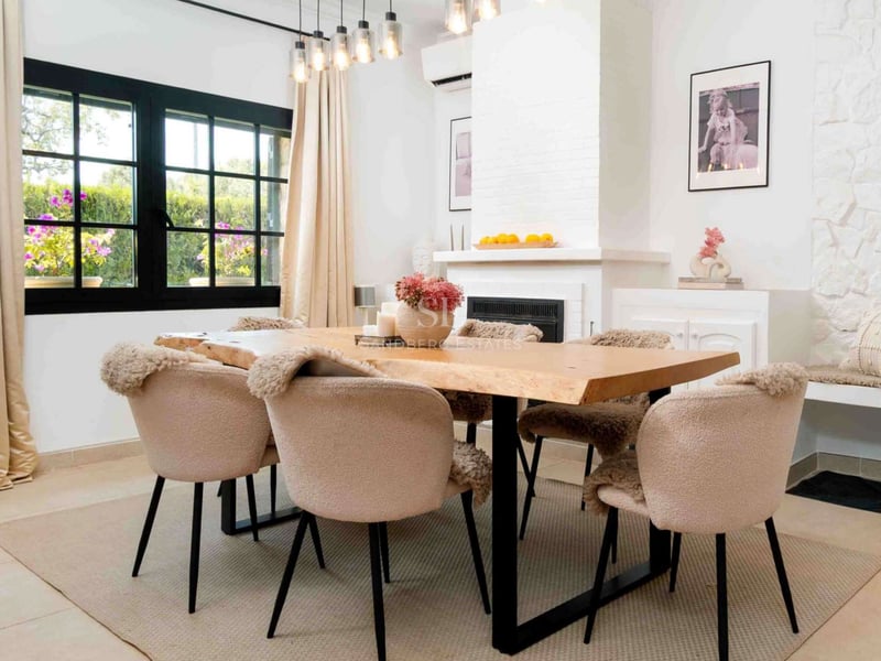 Salle à manger moderne avec table en bois naturel, chaises bouclées et cheminée blanche.