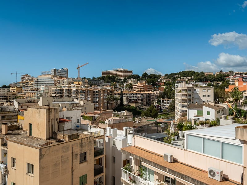Vue panoramique sur les toits d'une ville méditerranéenne et ses immeubles sous un ciel bleu clair.