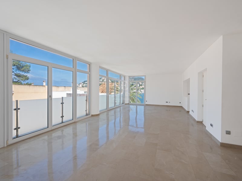 Salon moderne vide avec sol en marbre poli et grandes baies vitrées donnant sur la côte méditerranéenne.
