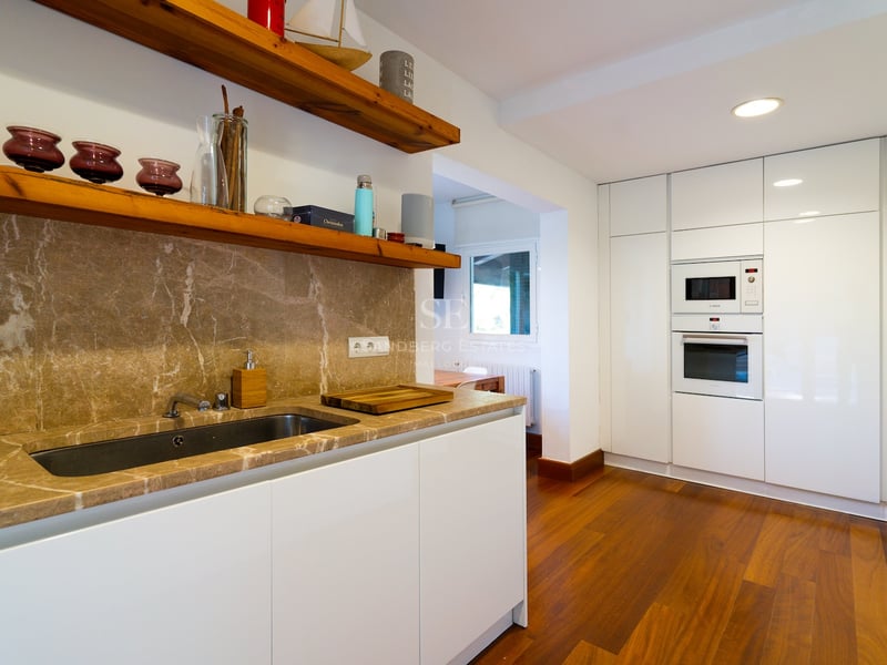Cuisine blanche contemporaine avec plans de travail en marbre brun, étagères en bois et appareils intégrés.