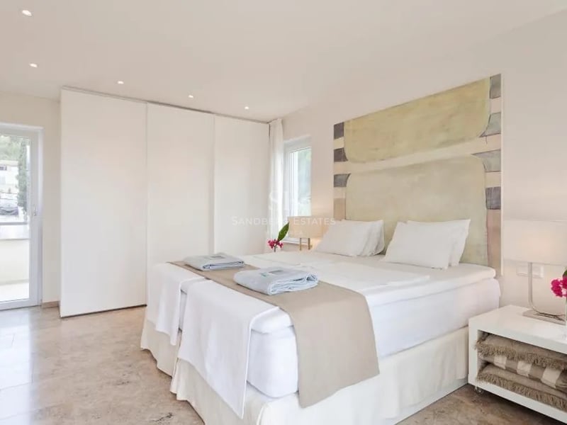 Chambre spacieuse blanche avec sol en marbre, placards intégrés et accès direct à la terrasse.