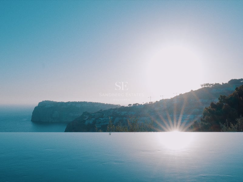 Littoral et collines se reflétant dans une piscine à débordement lors d'un coucher de soleil sur la Méditerranée.