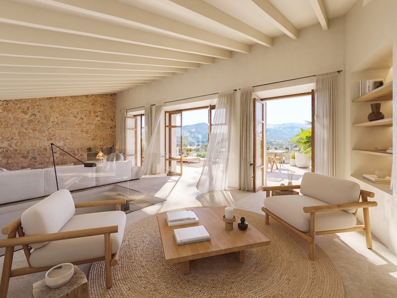 Salon spacieux avec murs en pierre, poutres apparentes et baies vitrées ouvrant sur une terrasse panoramique.