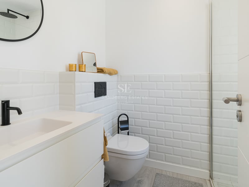 Salle de bain moderne avec carrelage métro blanc, robinetterie noire et lavabo minimaliste.