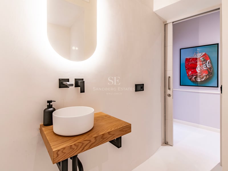 Vaste salon avec baies vitrées donnant sur la mer. Intérieur moderne avec mobilier élégant et lumière naturelle. Canapé beige, tapis clair, détails design.