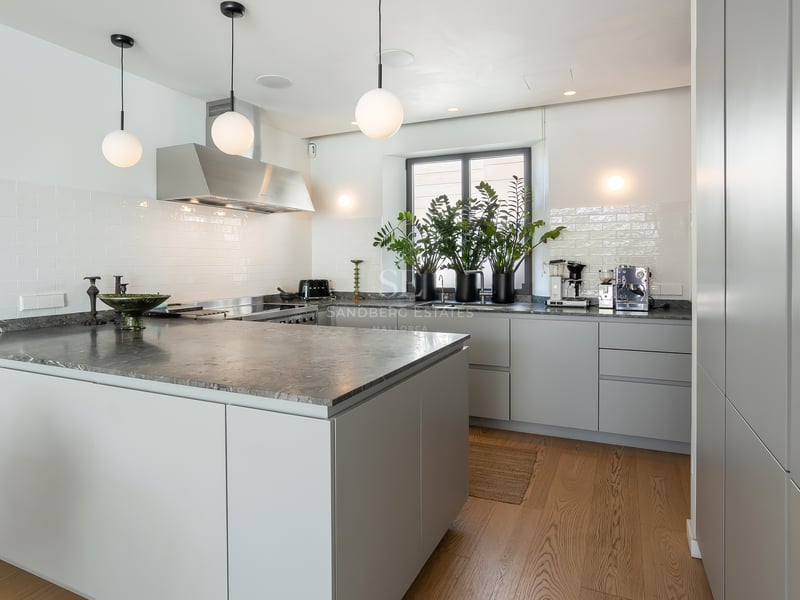 Cuisine contemporaine avec grand îlot en marbre gris, armoires grises minimalistes et suspensions globes blancs.