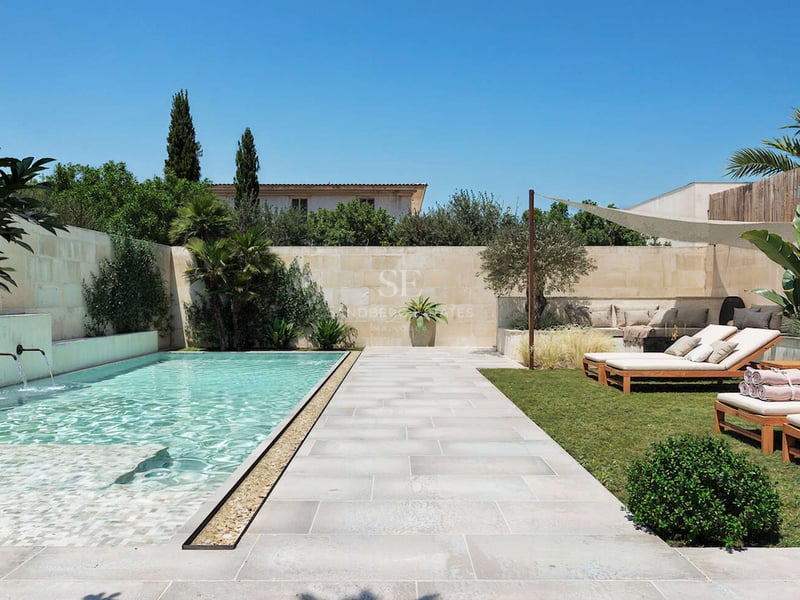 Piscine rectangulaire moderne avec jets d'eau, terrasse en pierre, bains de soleil en bois et plantes exotiques.