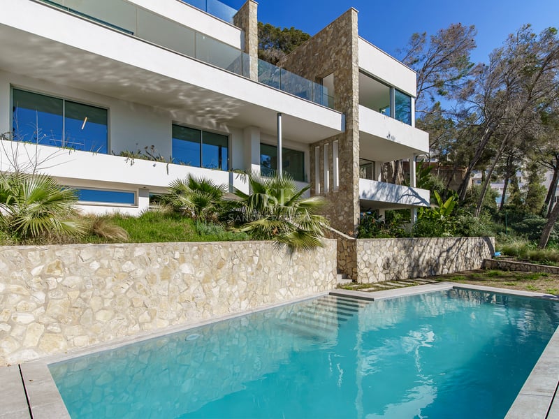 Villa moderne à plusieurs niveaux avec piscine turquoise, murs en pierre naturelle et balcons en verre.