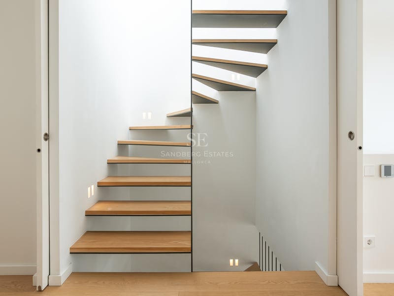 Escalier en colimaçon moderne avec marches en chêne et éclairage LED mural intégré.