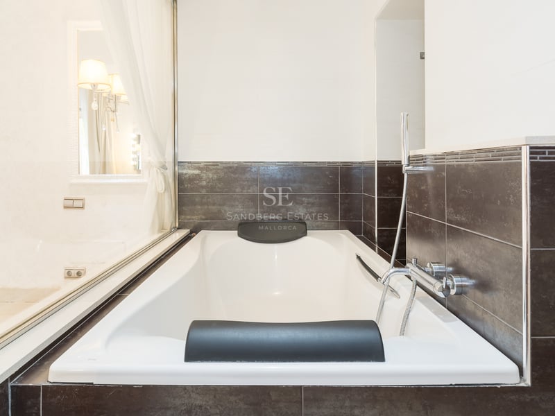Baignoire blanche avec appuie-tête noirs et carrelage marron foncé dans une salle de bain moderne.