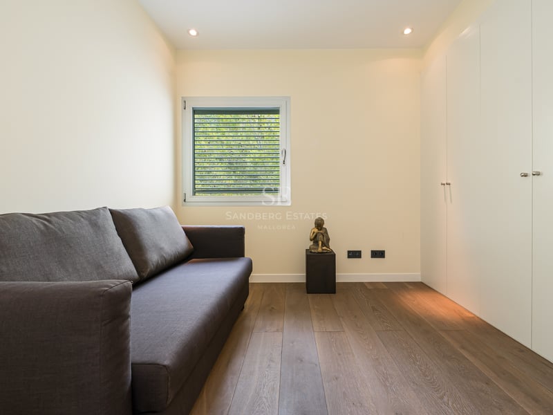 Chambre d'amis contemporaine avec canapé gris, parquet en chêne clair et grands placards intégrés blancs.