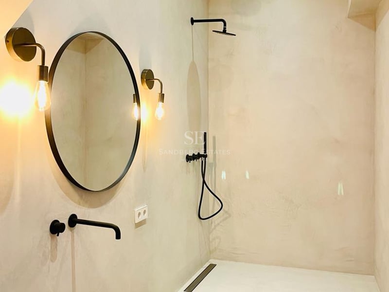 Douche à l'italienne moderne en microciment avec robinetterie noir mat et miroirs design.