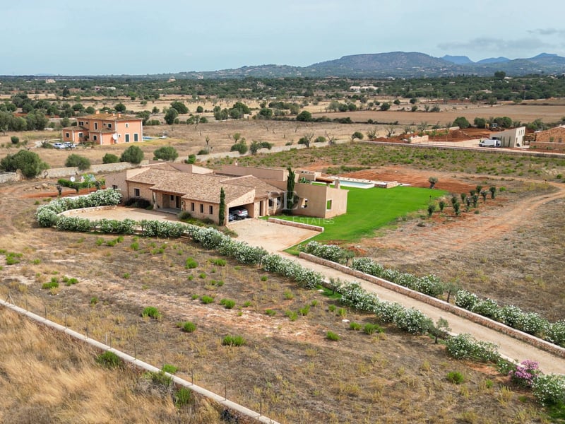 Vue aérienne d'une villa en pierre avec piscine et allée fleurie dans la campagne méditerranéenne.