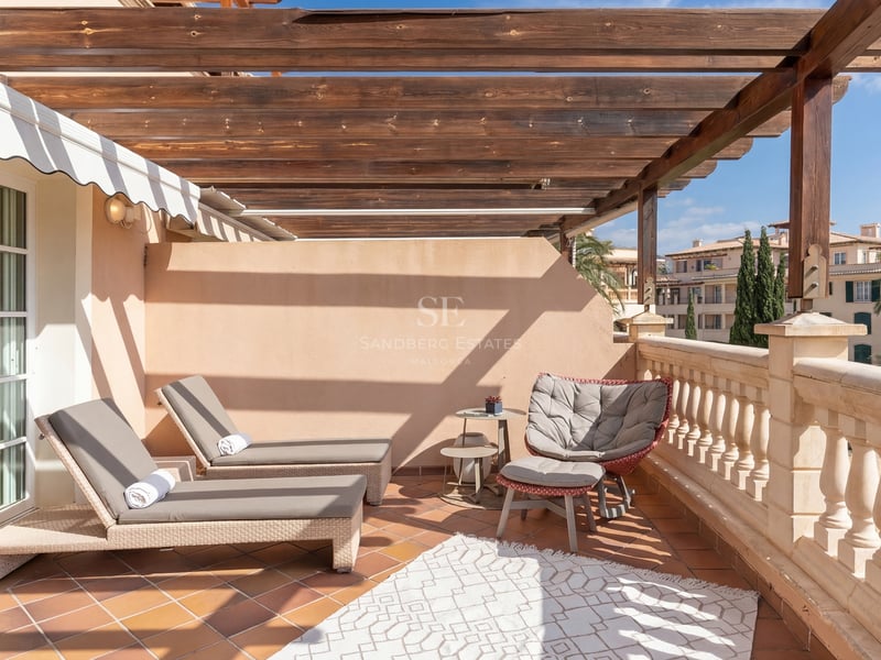 Terrasse ensoleillée avec pergola en bois, bains de soleil et sol en terre cuite.