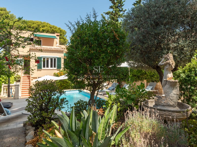 Piscine privée entourée de jardins méditerranéens, une statue classique et une villa aux tons terre cuite.
