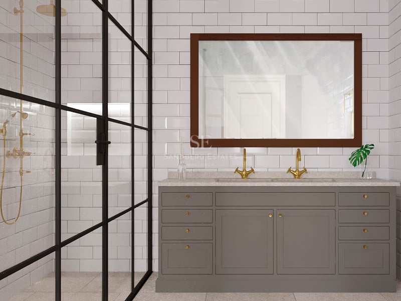 Salle de bain moderne avec double vasque grise, robinets dorés et douche vitrée à cadre noir sur carrelage métro blanc.