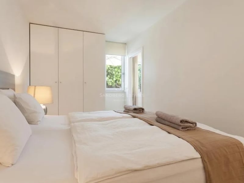 Chambre blanche lumineuse avec lits jumeaux, placards intégrés et vue sur la verdure.
