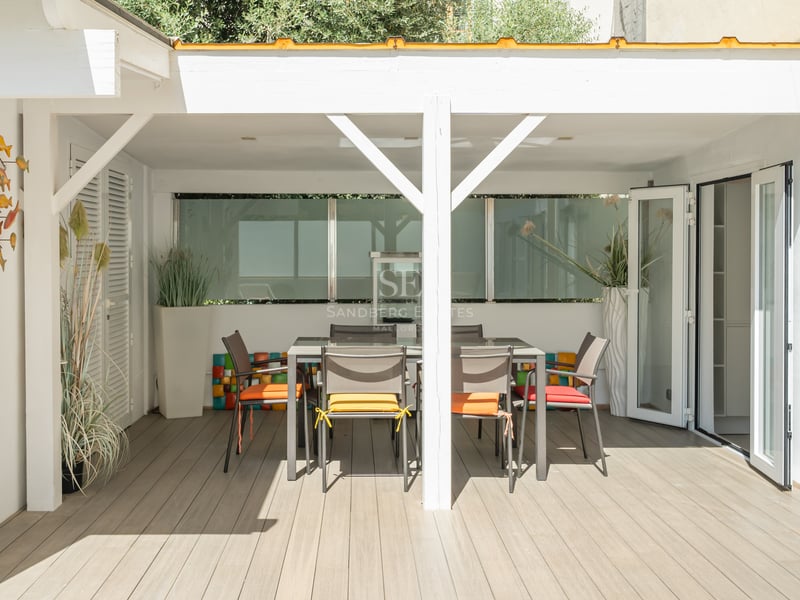 Grande piscine bordée de transats, avec une maison moderne au design minimaliste à l'arrière-plan et une végétation luxuriante.