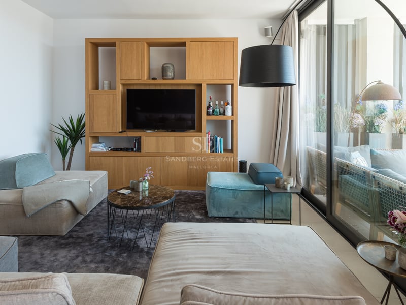 Salon lumineux avec canapés modulables en velours, table basse en marbre et baies vitrées ouvrant sur une terrasse.