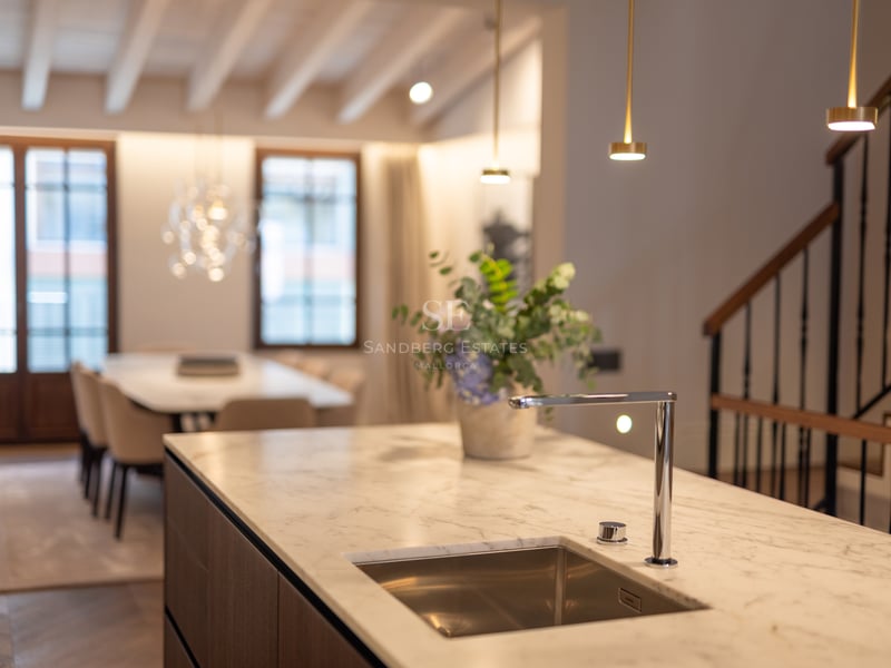 Îlot de cuisine moderne avec comptoir en marbre blanc, robinet chromé et évier intégré, face à la salle à manger.