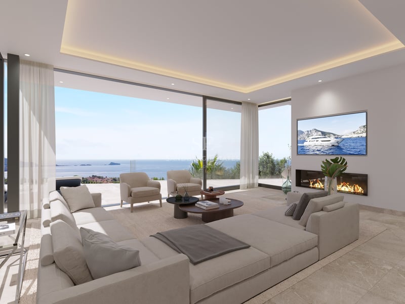 Salon contemporain avec grand canapé beige, cheminée linéaire et baies vitrées donnant sur la mer Méditerranée.