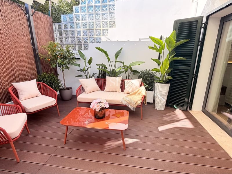 Terrasse avec terrasse en bois, mobilier d'extérieur rouge terre cuite et plantes décoratives sous la lumière naturelle.