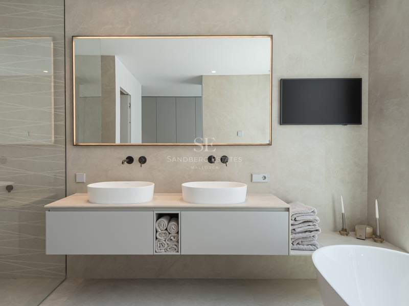 Salle de bains moderne avec double vasque suspendue, miroir rétroéclairé, robinetterie noir mat et baignoire îlot.