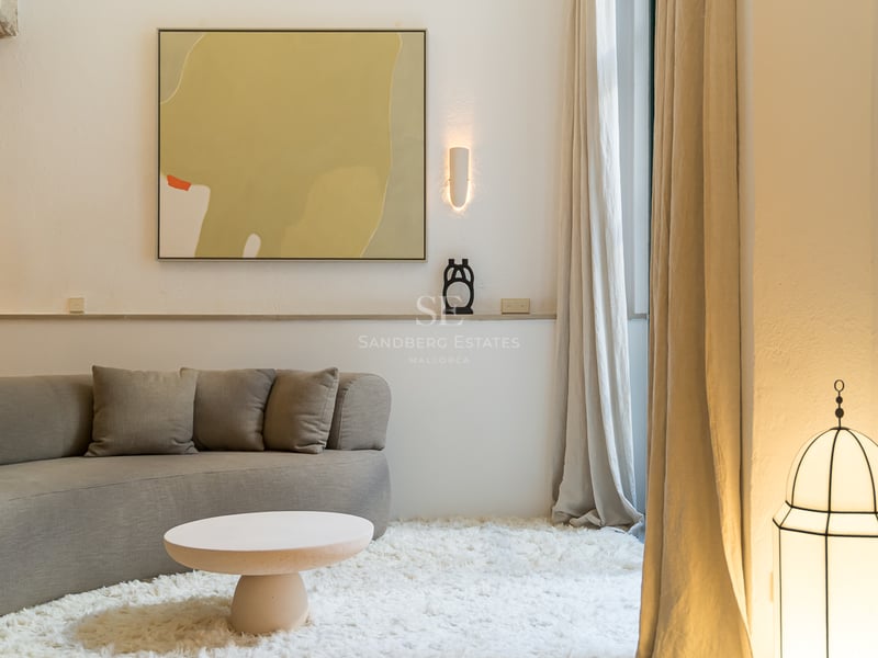 Un salon confortable avec un canapé incurvé gris, un tapis blanc à poils longs et de l'art abstrait.