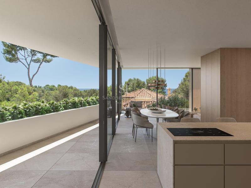 Salle à manger moderne à aire ouverte avec îlot de cuisine et grandes baies vitrées ouvrant sur une terrasse et la mer.