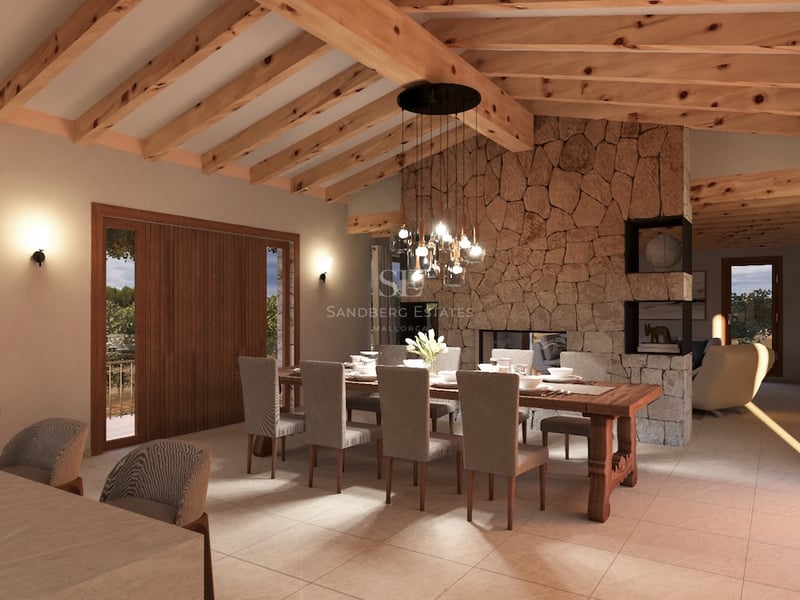 Vue d'une salle à manger de luxe avec poutres apparentes, mur en pierre naturelle et grande table en bois massif.