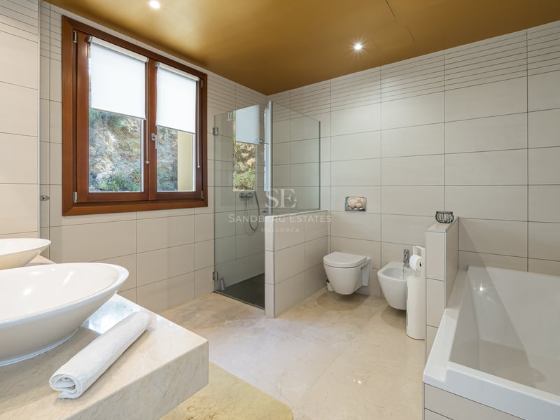 Salle de bains spacieuse avec double vasque, baignoire, douche à l'italienne et finitions en marbre beige.