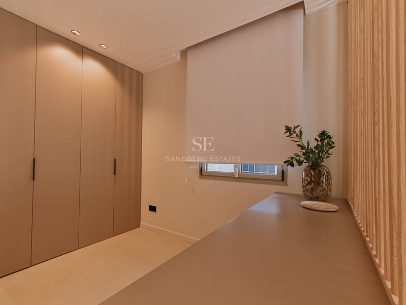 Chambre minimaliste avec placards sur mesure couleur taupe, fenêtre avec store enrouleur et console élégante.