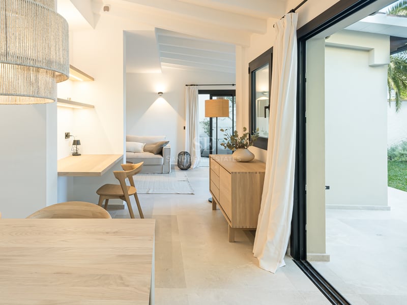 Salon contemporain en chêne clair avec coin bureau et larges baies vitrées ouvrant sur une terrasse ensoleillée.