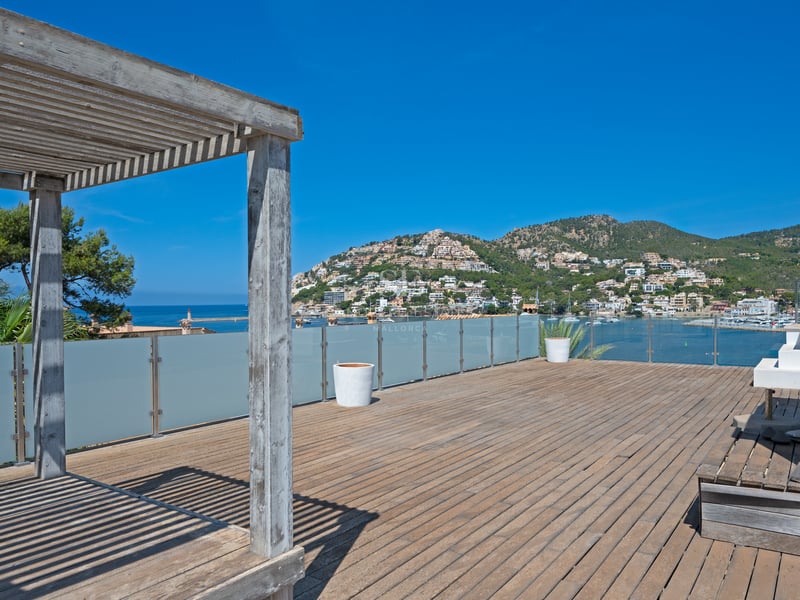 Grande terrasse en bois sur le toit avec pergola offrant une vue sur le port méditerranéen et les collines environnantes.